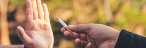Hand offering a lit cigarette to someone who is holding out their hand as a rejection